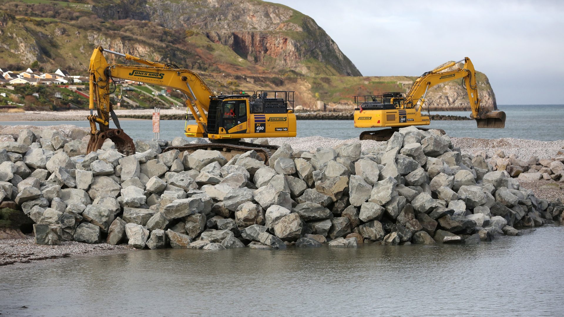 Jones Bros placing some of the 70,000 tonnes of locally sourced rock armour coastal defence into place at Penrhyn Bay