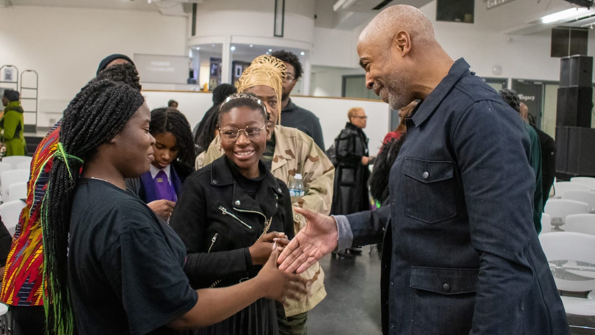 Eric Collins, CEO of Impact X, shakes hands with delegates at an event.