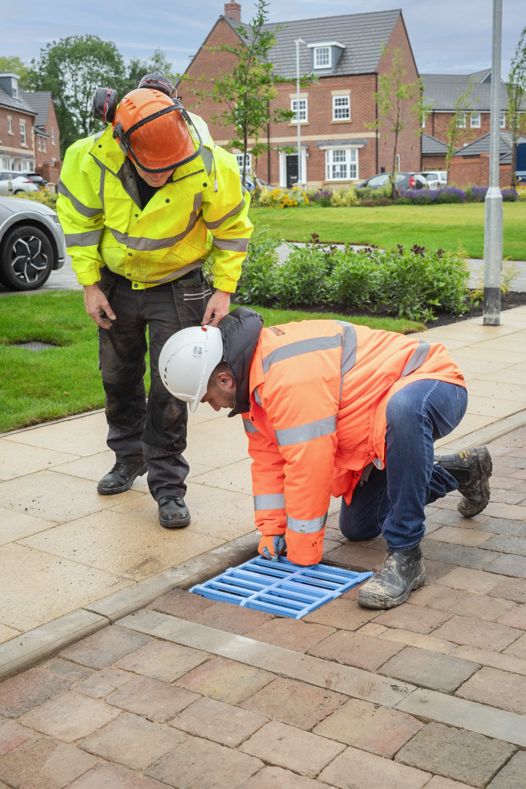 One of The Sea Starts Here's bright blue gully grate being installed 